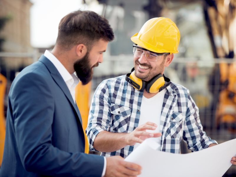 Un professionista che indossa diversi dispositivi di protezione individuale, mentre comunica i suoi progetti ad un formatore Scait